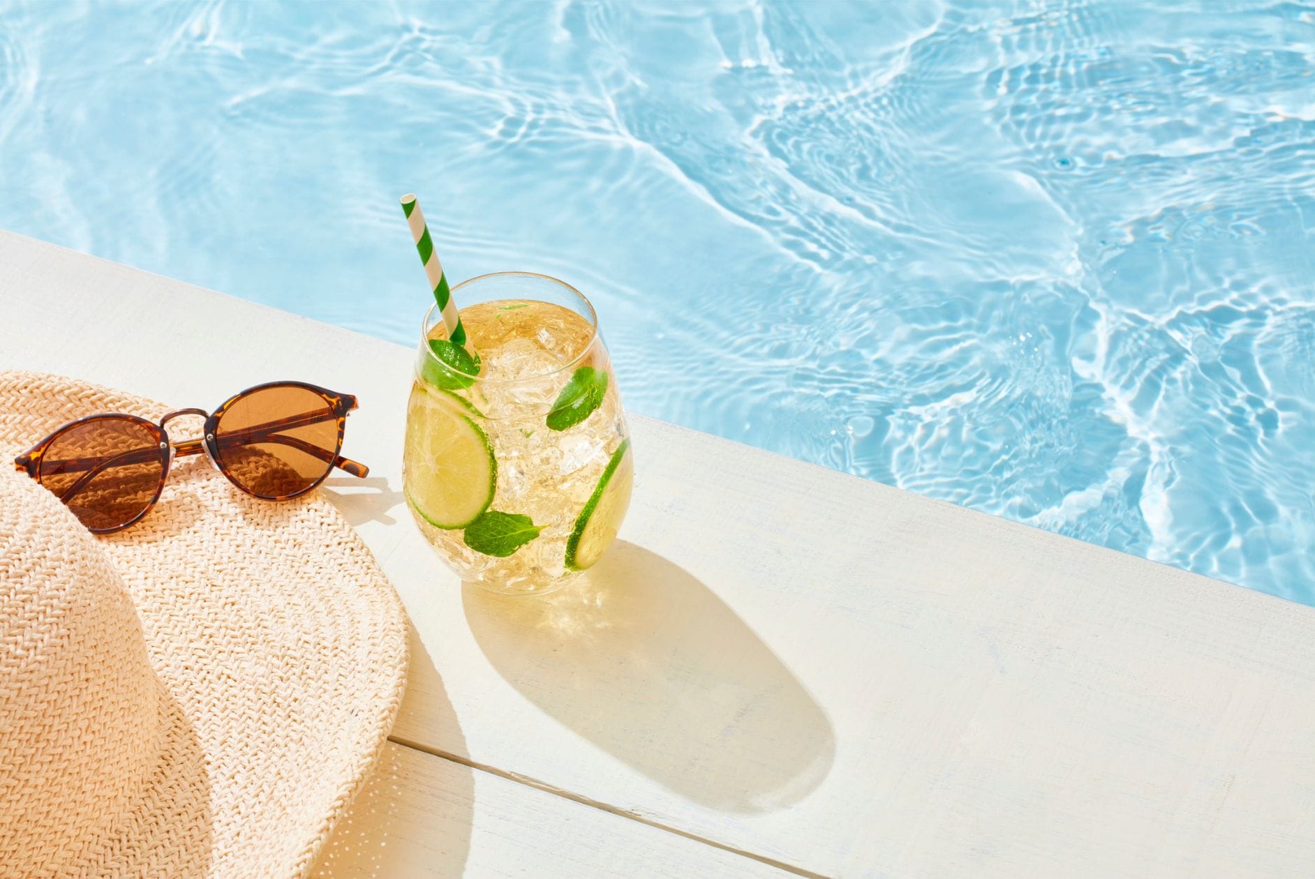 Pool mit Glas Limonade, Hut und Sonnenbrille